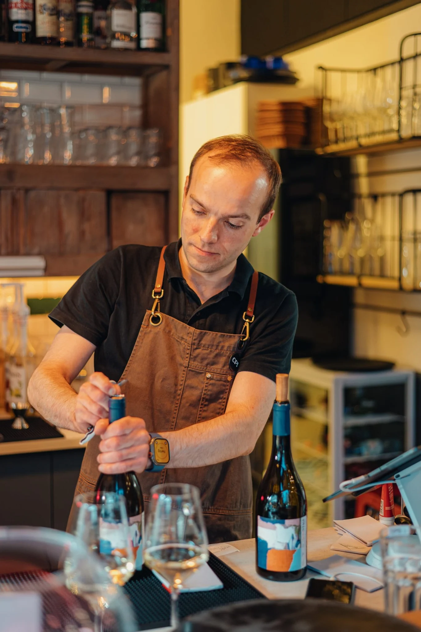 Mitarbeiter von Chez Pippo öffnet eine Weinflasche an der Bar